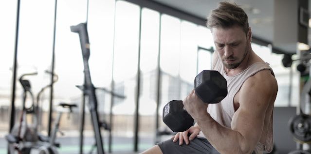A man in a gym lifting up dumbbells to strengthen his muscles